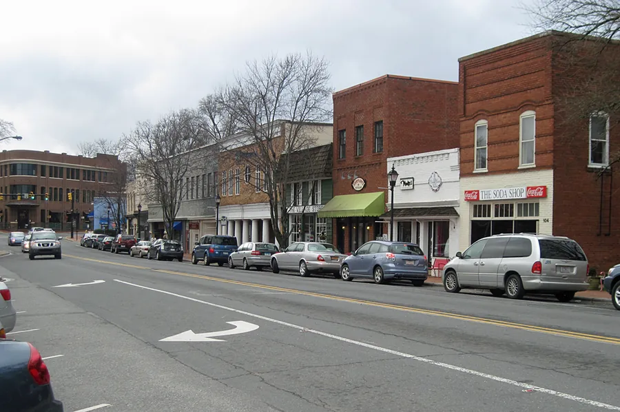 Two-story brick storefronts with awnings and angled parking along Main Street in Davidson, North Carolina, on a gray winter day
